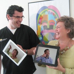 man and woman smiling and holding iPad with funny photos