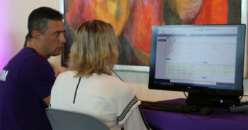 Senior UX designer in purple shirt working with woman on computer