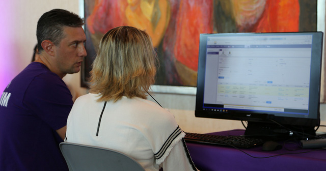 Senior UX designer in purple shirt working with woman on computer