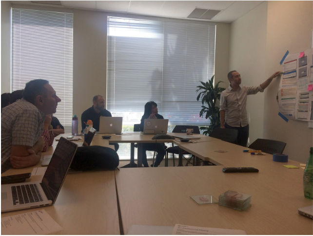 group of employees in a conference room with laptops watching a presenter