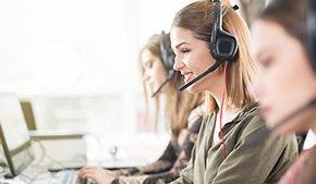 women in call center wearing headsets and using laptops