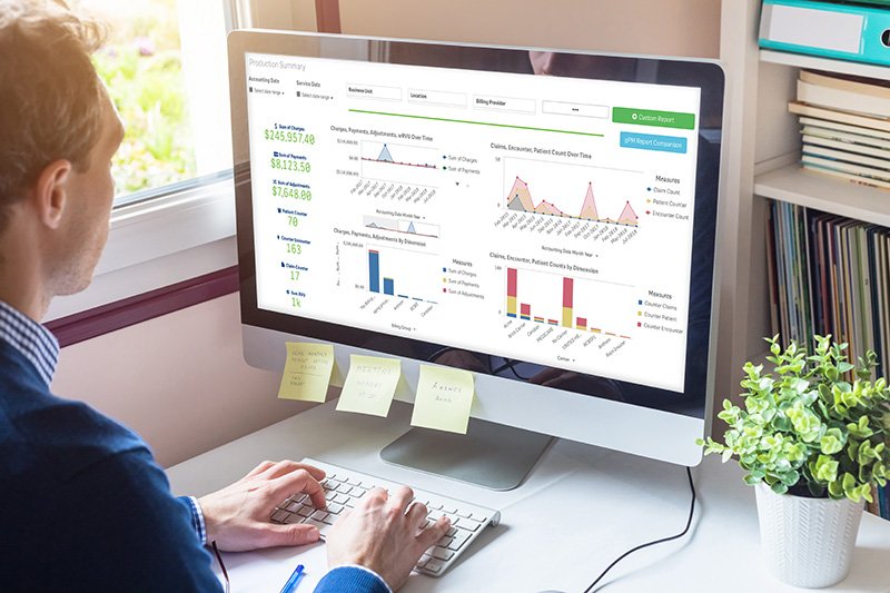 man in business attire working on a desktop computer with charts and graphs