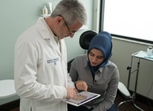 doctor and patient in exam room both pointing at iPad