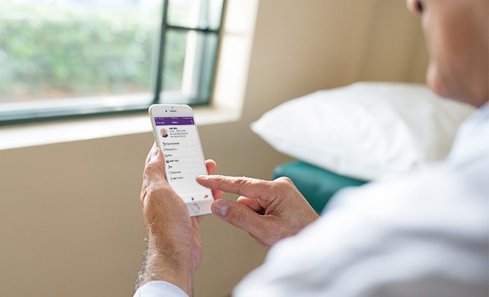 doctor using PocketEMA app on iPhone in front of window doctor using PocketEMA app on iPhone in front of window