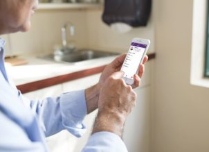 Image of physician recording notes in allergy-specific software on phone Image of physician recording notes in allergy-specific software on phone
