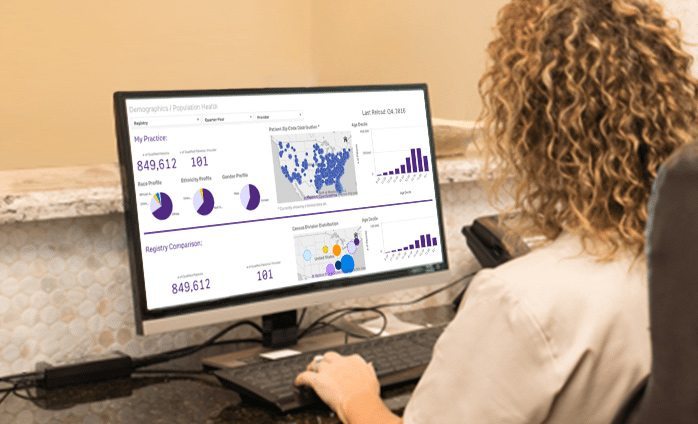 Woman sitting at desk reviewing software on computer screen