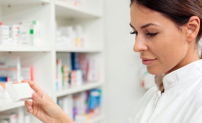 Woman in medical supply room reading product label on medication package Woman in medical supply room reading product label on medication package