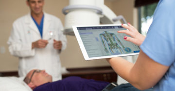 medical assistant using orthopedic ipad ehr with patient laying on table and orthopedic surgeon