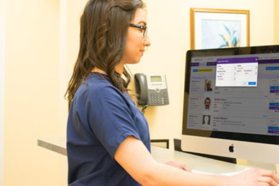 Woman reviewing patient charts on computer screen