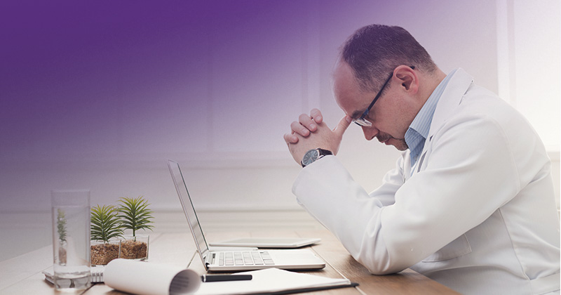 doctor in white lab coat frustrated staring at laptop