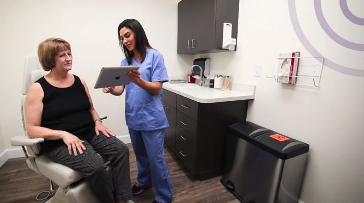 medical assistant reviewing medical records with a female patient from a tablet