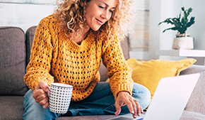 Woman drinking coffee and using laptop computer