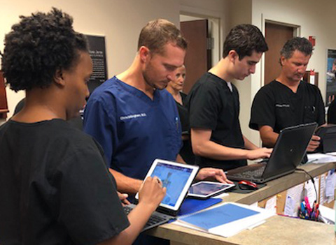 medical assistants using orthopedic EHR in office standing at front desk