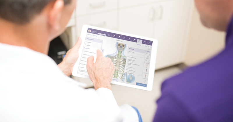 Physician showing a patient images on an iPad with orthopedic EHR software 