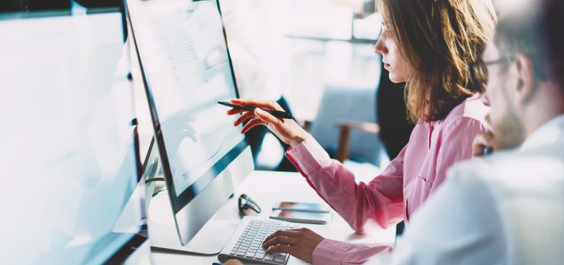 A biling specialist showing graphs on screen to coworker