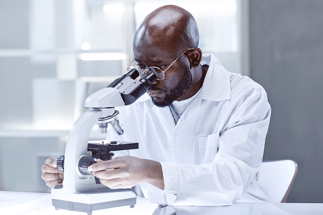 Dermatopathologist analyzing lab samples with a microscope, supported by digital pathology software for efficient documentation and billing