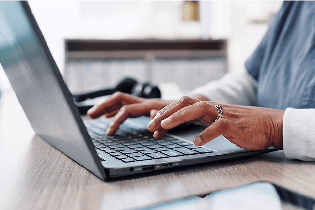 A healthcare professional typing on their laptop.