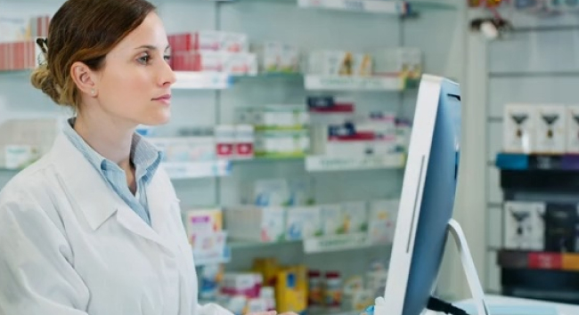 A provider in a white coat uses an EHR on a desktop to manage inventory in a medical supply room.