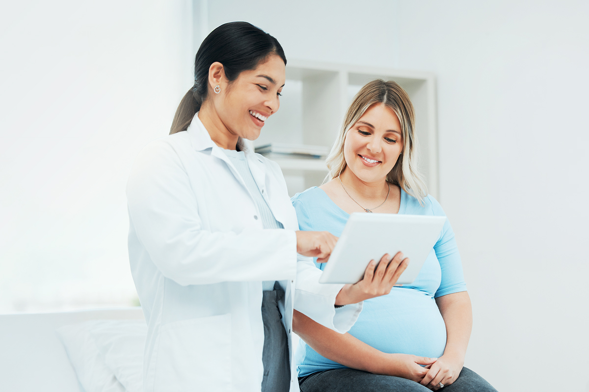 An image of an OBGYN using her iPad and consulting with a patient.
