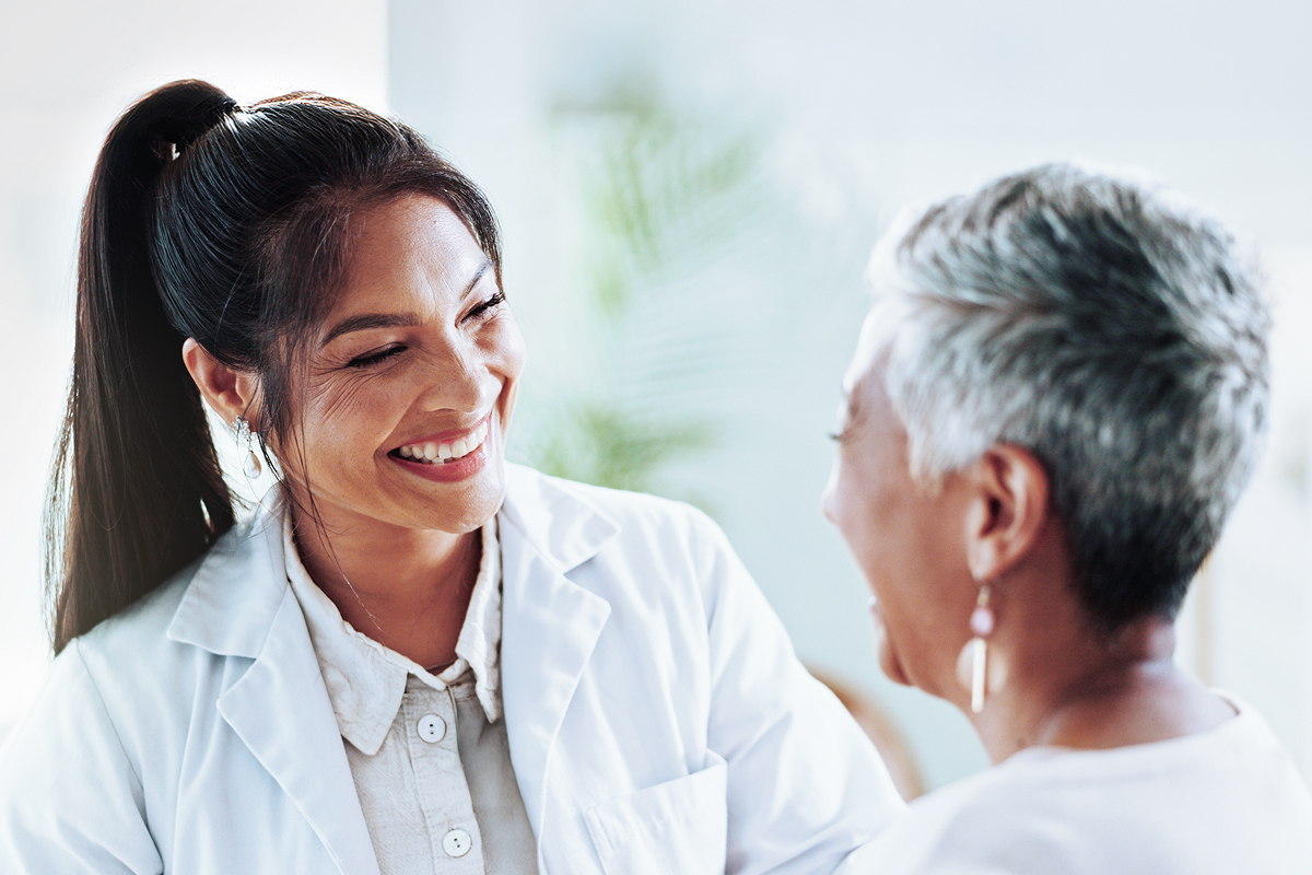 A smiling physician enjoys a pleasant interaction with her patient, showing the human connection improved by a modern EHR.