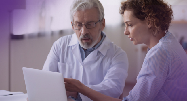 Image of a provider and admin team member reviewing EHR notes on screen.