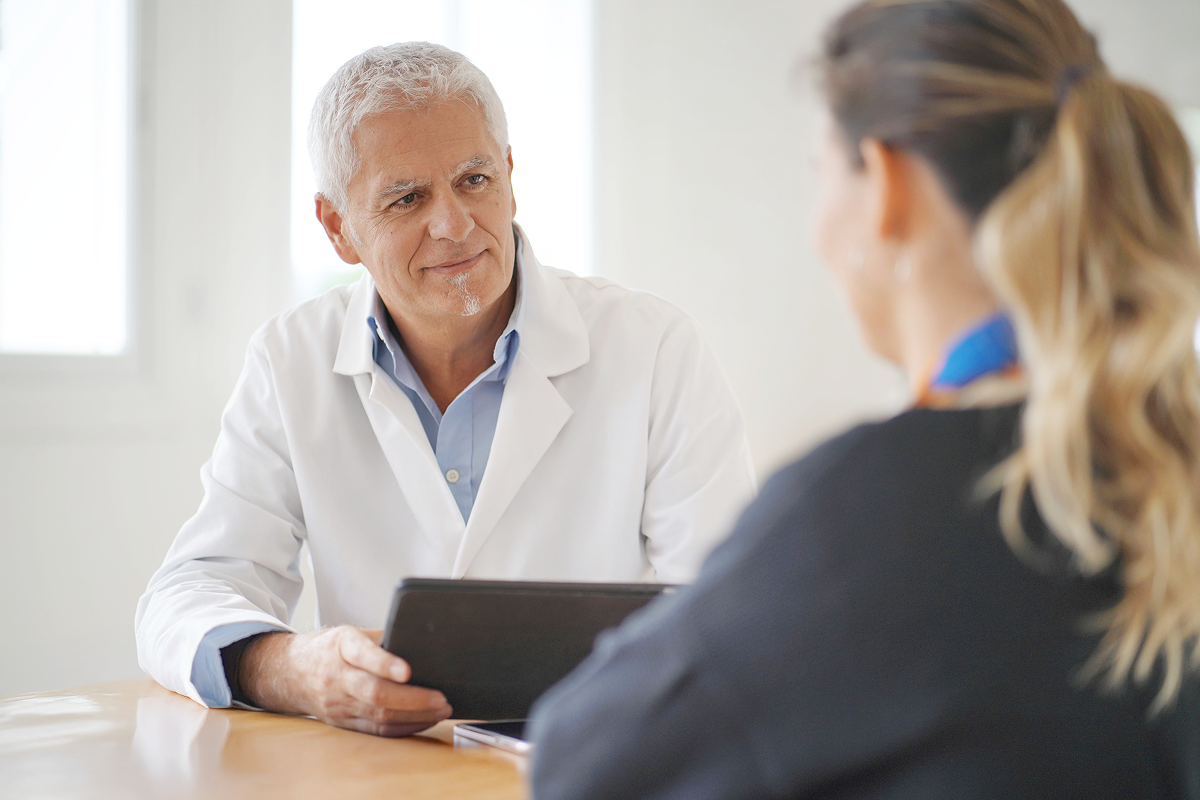 Image of doctor discussing care with patient and holding iPad