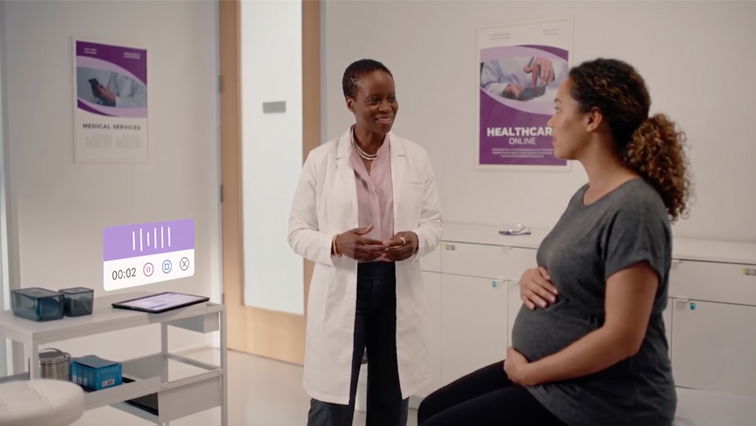A doctor smiling and talking to a pregnant patient in an exam room