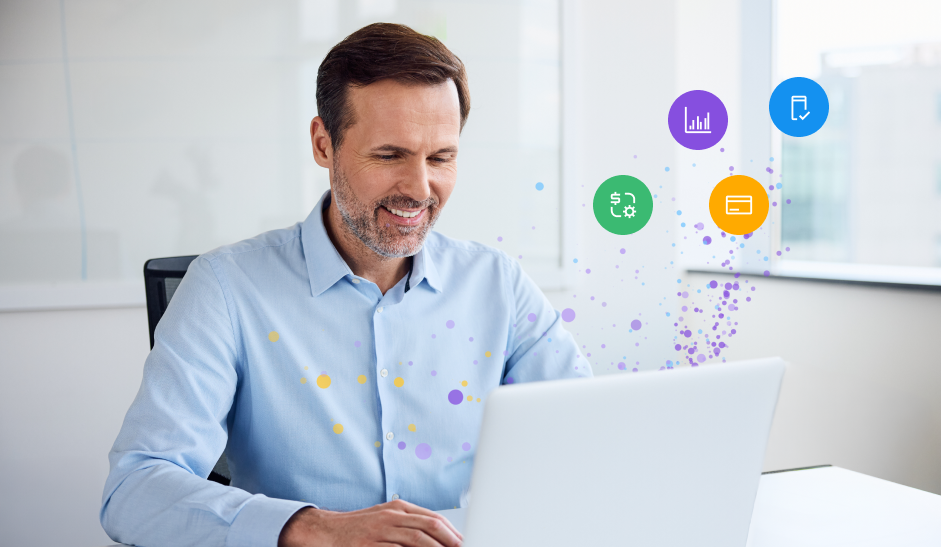 Un hombre sonriente con una camisa azul claro trabajando con un ordenador portátil en un escritorio, junto a unos iconos de colores que flotan en el aire y representan el análisis de datos, un documento aprobado, la gestión financiera y una tarjeta de crédito.