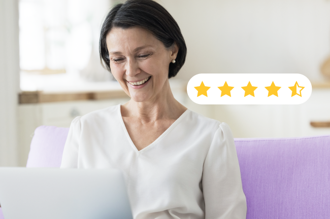 Una mujer mayor sonriente, sentada en un sofá morado y mirando un ordenador portátil, junto a una superposición digital que muestra una valoración de cuatro estrellas y media sobre cinco.