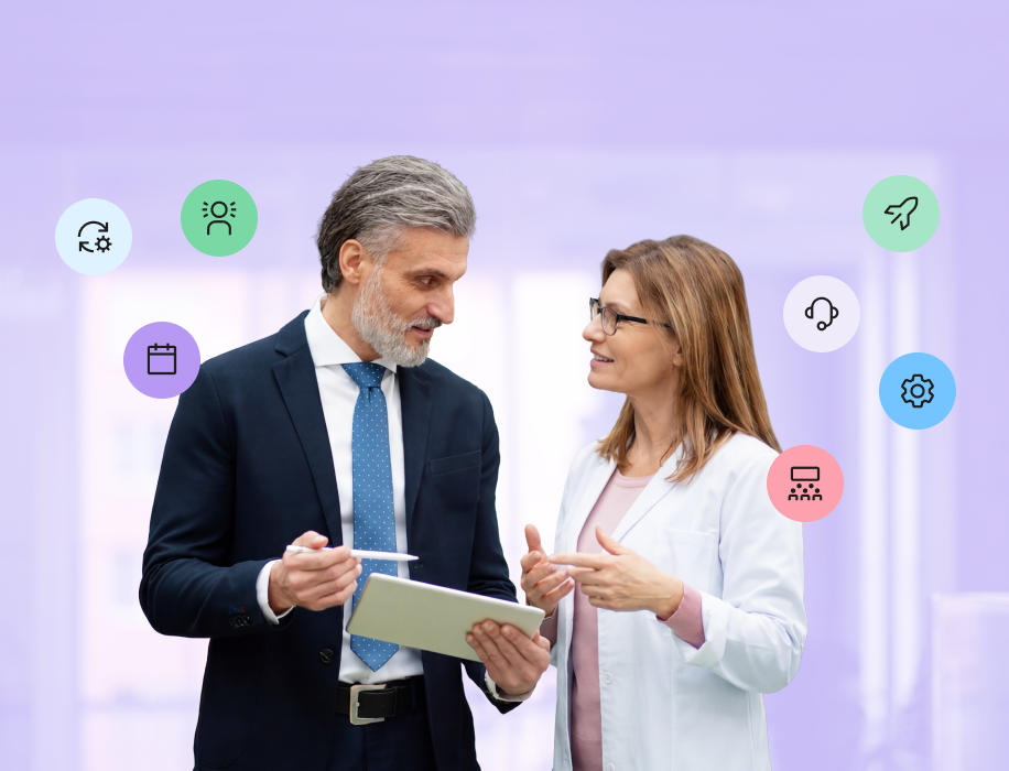 A businessman holding a tablet and stylus conversing with a female healthcare professional in a white coat, surrounded by floating colorful icons representing synchronization, user profiles, a calendar, a rocket ship, customer support, settings, and team training.